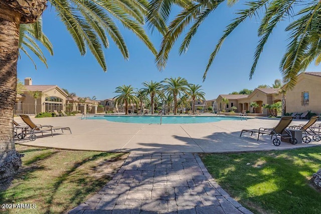 community pool with a patio area and fence
