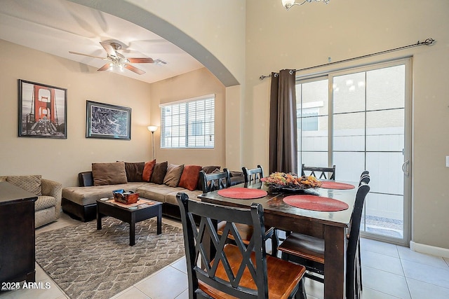living room with light tile patterned flooring, ceiling fan, arched walkways, and baseboards