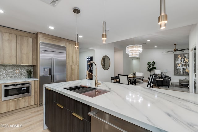 kitchen with backsplash, pendant lighting, appliances with stainless steel finishes, and sink