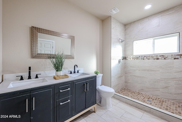 bathroom with vanity, toilet, and tiled shower