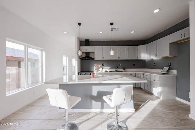 kitchen with gray cabinetry, light stone countertops, a center island, and pendant lighting