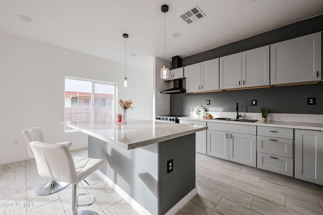 kitchen featuring a center island, a kitchen breakfast bar, sink, hanging light fixtures, and light stone countertops