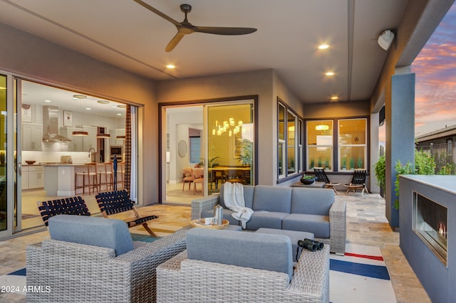 patio terrace at dusk featuring ceiling fan and an outdoor living space