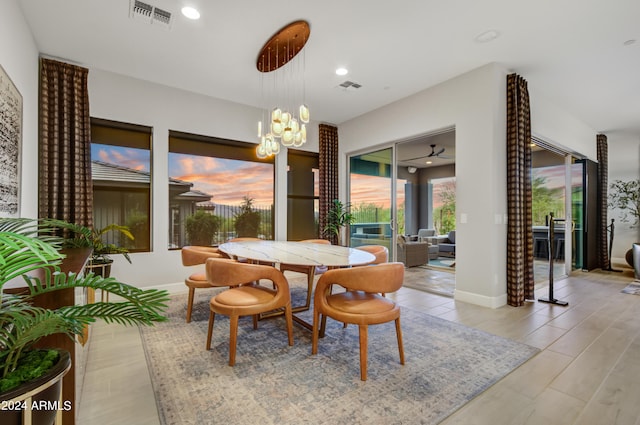 dining space featuring ceiling fan with notable chandelier and light hardwood / wood-style flooring