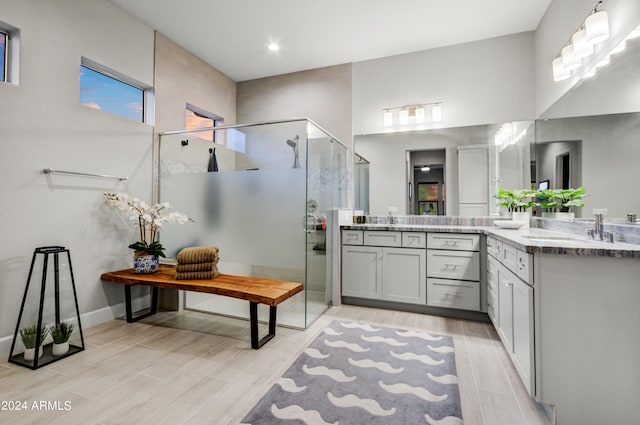 bathroom with a high ceiling, hardwood / wood-style floors, a shower with shower door, and vanity