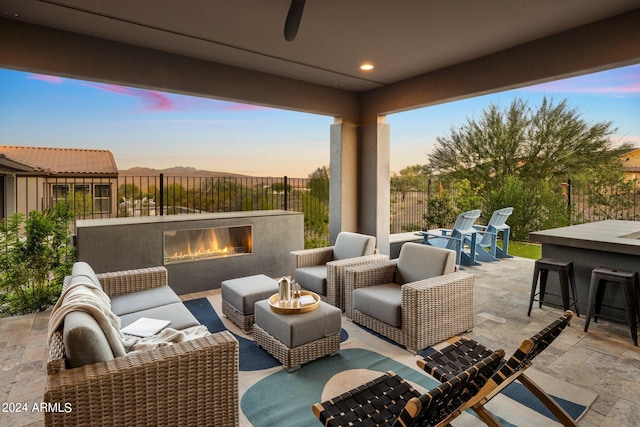 patio terrace at dusk featuring an outdoor living space with a fireplace