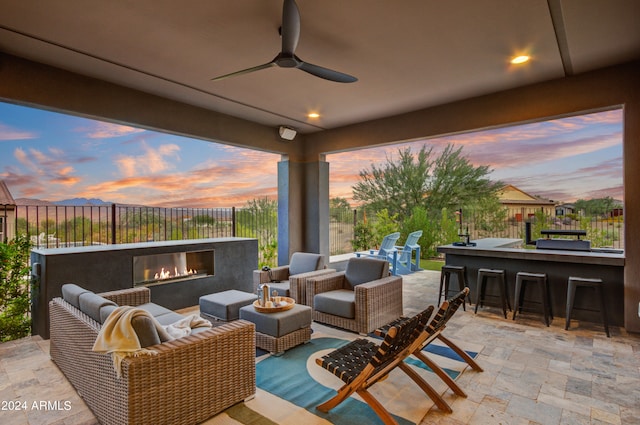 patio terrace at dusk featuring ceiling fan, an outdoor living space, and an outdoor bar