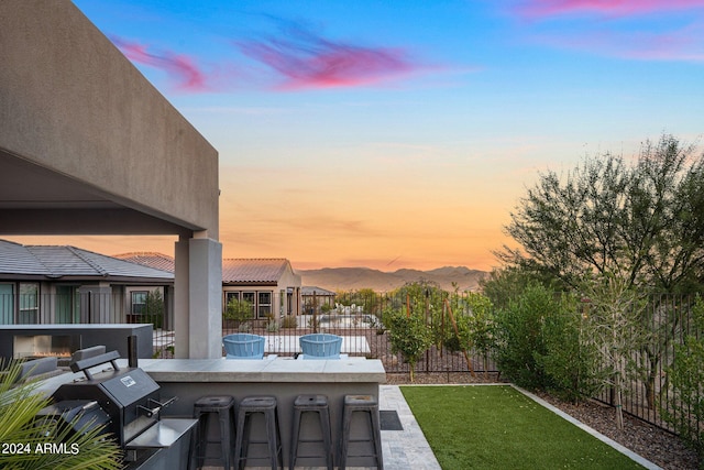 exterior space featuring a mountain view, an outdoor bar, area for grilling, and a patio