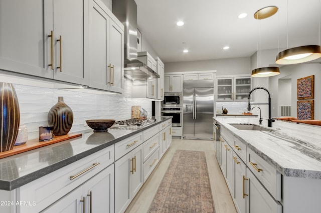 kitchen with built in appliances, decorative light fixtures, a large island, and wall chimney range hood