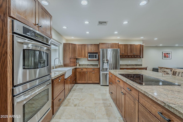 kitchen with recessed lighting, stainless steel appliances, a sink, visible vents, and light stone countertops