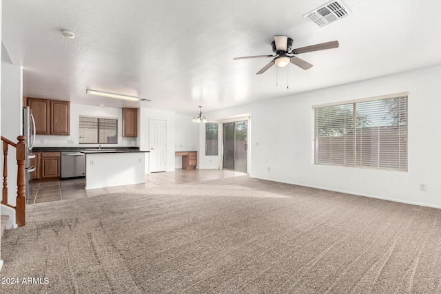 unfurnished living room with a textured ceiling, ceiling fan with notable chandelier, and light carpet