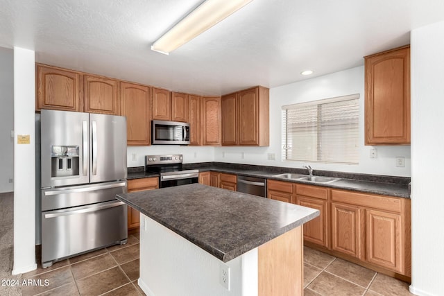 kitchen with dark tile patterned floors, sink, a kitchen island, and stainless steel appliances