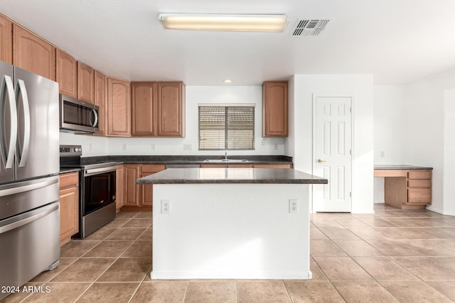 kitchen with a kitchen island, light tile patterned floors, sink, and appliances with stainless steel finishes