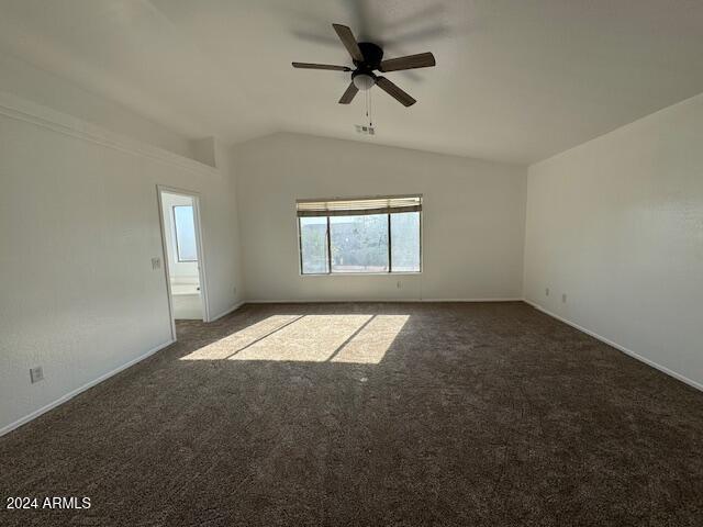 empty room featuring ceiling fan, dark carpet, and vaulted ceiling