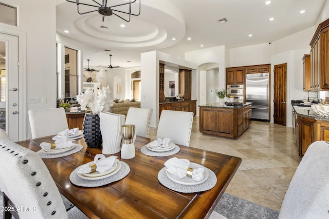 dining area featuring visible vents, a tray ceiling, recessed lighting, arched walkways, and ceiling fan