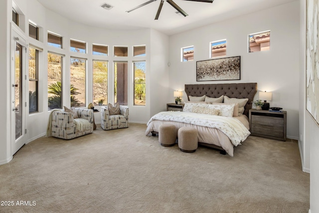 carpeted bedroom with visible vents, a ceiling fan, baseboards, and a towering ceiling