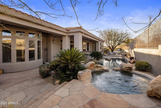 view of patio featuring an in ground hot tub and fence