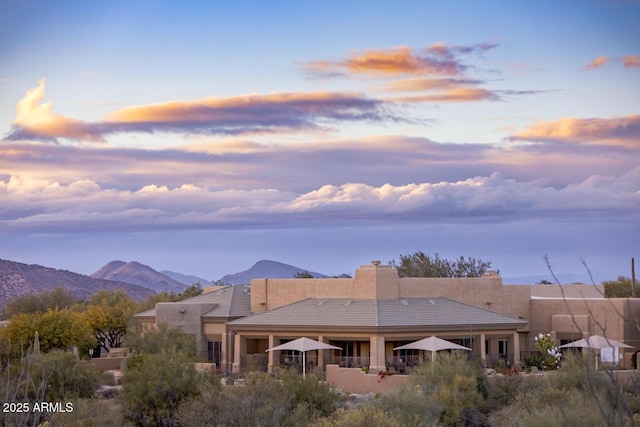 rear view of house with a mountain view, stucco siding, and a tiled roof