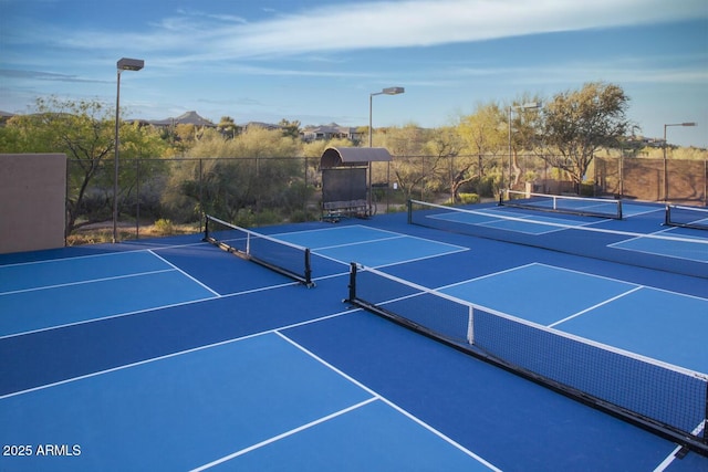 view of tennis court featuring community basketball court and fence