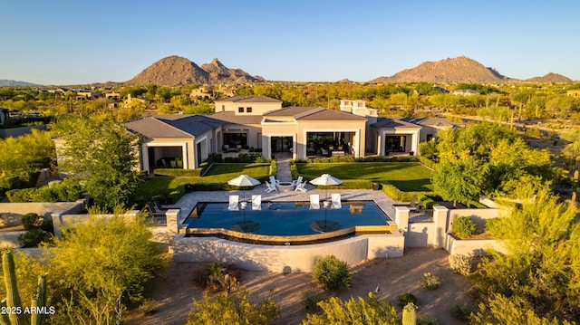 back of house with an outdoor pool, fence, a mountain view, and stucco siding
