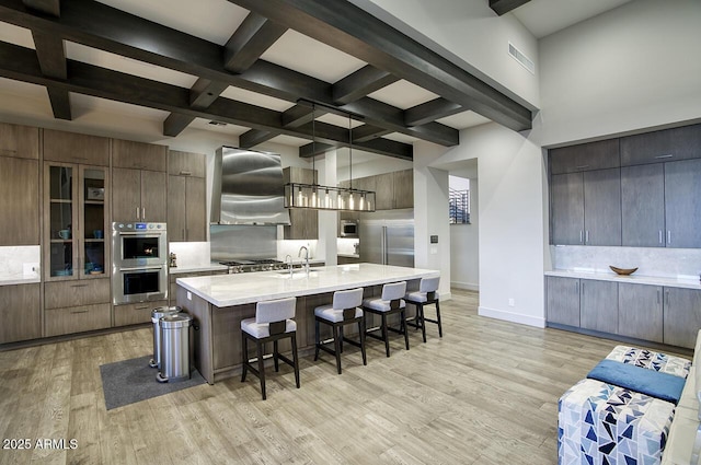 kitchen with wall chimney range hood, stainless steel appliances, modern cabinets, and tasteful backsplash