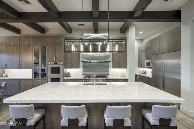kitchen featuring backsplash, appliances with stainless steel finishes, a sink, beamed ceiling, and light wood finished floors