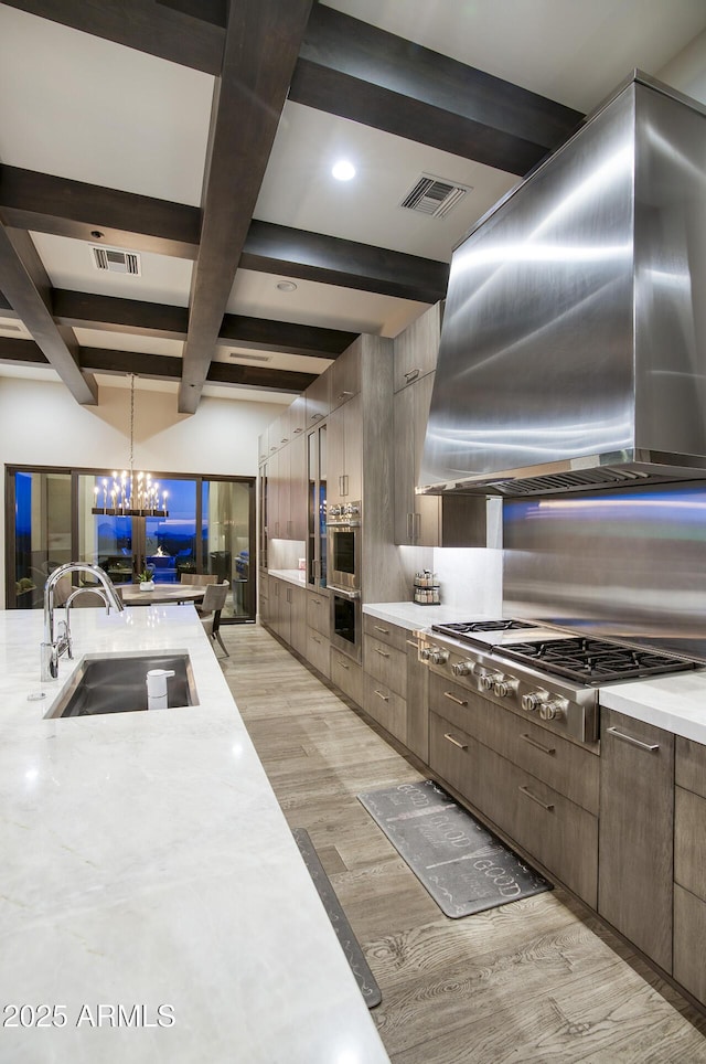 kitchen featuring a sink, extractor fan, light wood-style flooring, visible vents, and coffered ceiling