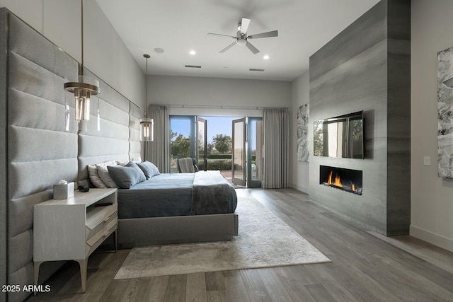 bedroom featuring access to outside, a fireplace, baseboards, wood finished floors, and visible vents
