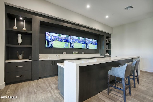 bar featuring visible vents, built in features, baseboards, recessed lighting, and light wood-style flooring