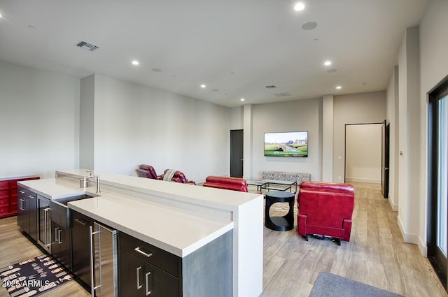 kitchen with light countertops, open floor plan, visible vents, and a sink