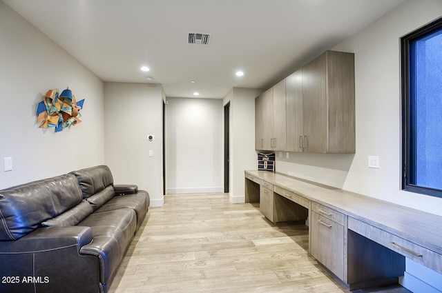 office space featuring built in desk, light wood finished floors, recessed lighting, baseboards, and visible vents