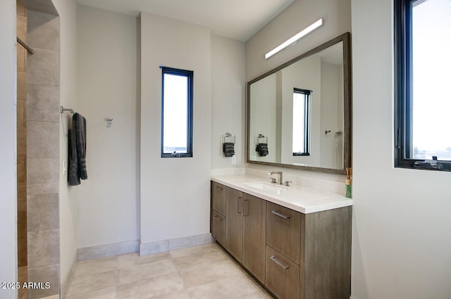 full bathroom featuring vanity, baseboards, tile patterned floors, and tiled shower
