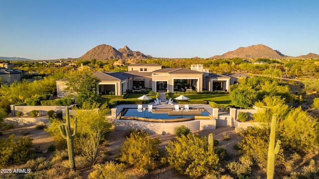 rear view of property with stucco siding, a mountain view, and a yard
