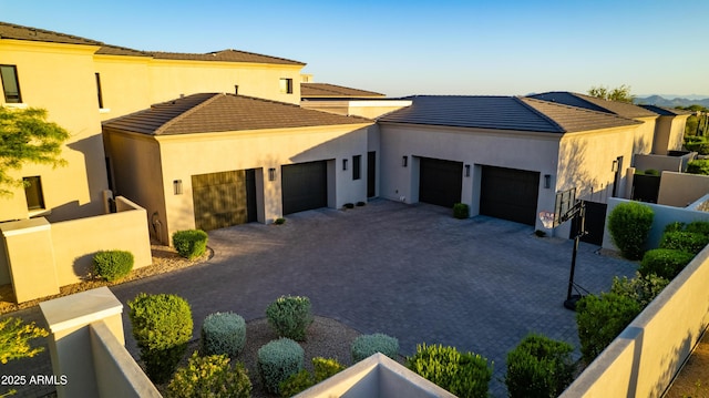 view of front of property featuring an attached garage, decorative driveway, stucco siding, and a tiled roof