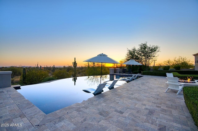 pool at dusk featuring a patio