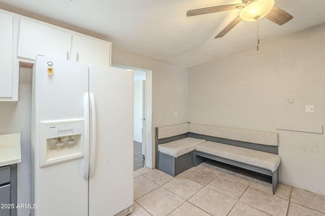 kitchen featuring light tile patterned floors, light countertops, white refrigerator with ice dispenser, and white cabinetry