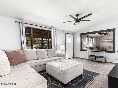 living room with ceiling fan, vaulted ceiling, and light tile patterned floors