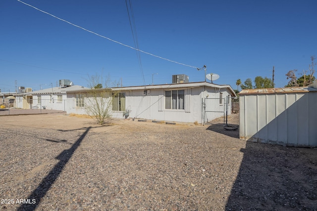 rear view of house featuring an outbuilding, crawl space, a gate, fence, and a shed