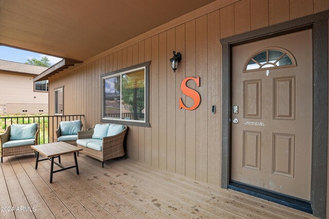 view of exterior entry with a deck and an outdoor living space