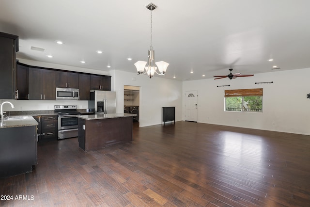 kitchen featuring light stone counters, dark wood-type flooring, stainless steel appliances, and a kitchen island