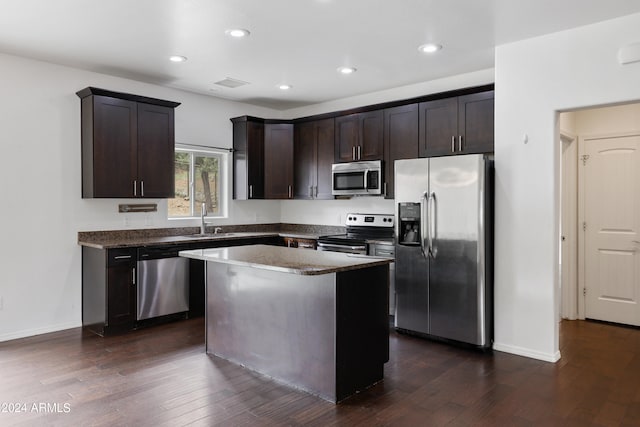 kitchen featuring dark wood-type flooring, stainless steel appliances, sink, and a kitchen island