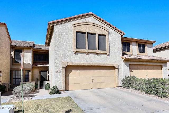 view of property with an attached garage, a tiled roof, and stucco siding