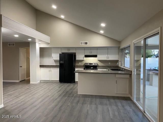 kitchen with a sink, visible vents, freestanding refrigerator, stainless steel electric stove, and dark countertops