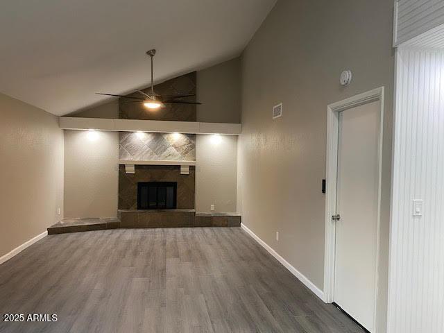 unfurnished living room featuring a large fireplace, baseboards, visible vents, and wood finished floors