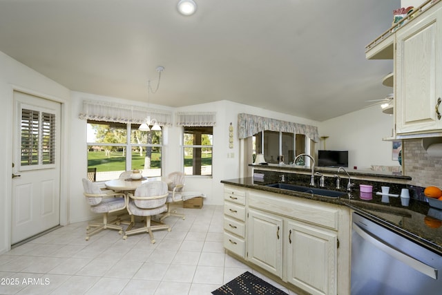 kitchen with dishwasher, dark stone countertops, pendant lighting, sink, and plenty of natural light