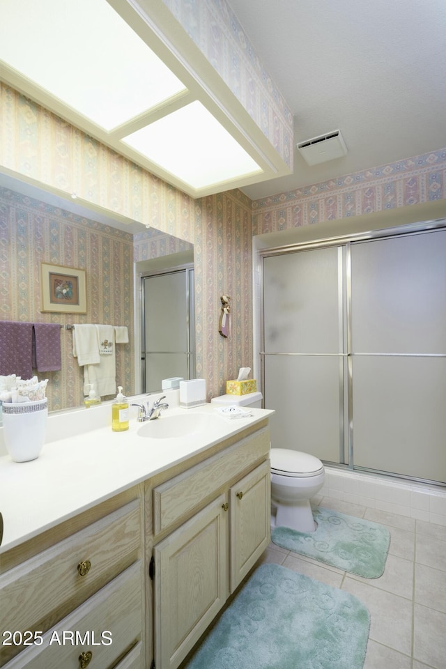 bathroom featuring tile patterned floors, vanity, toilet, and walk in shower