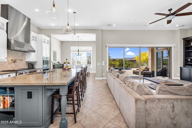 37308 N 100th Pl, Scottsdale, AZ 85262 - kitchen featuring wall chimney range hood, light stone counters, open shelves, open floor plan, and a ceiling fan