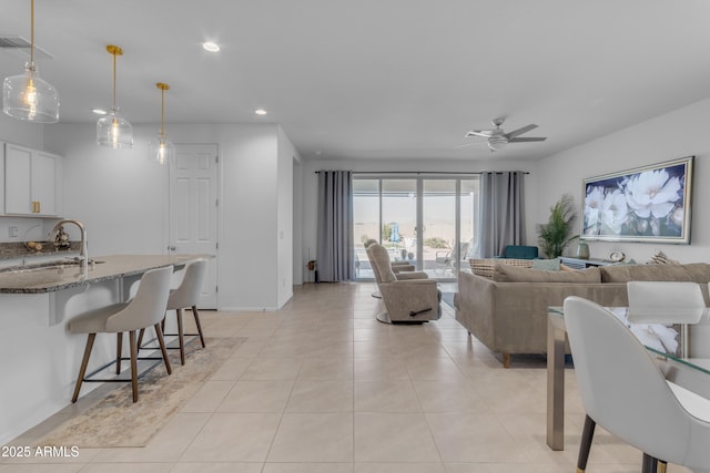 tiled living room featuring ceiling fan and sink