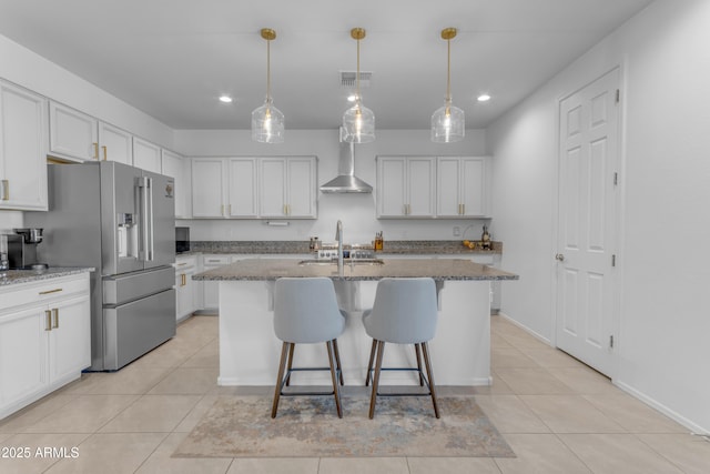 kitchen with sink, light stone countertops, an island with sink, high end fridge, and white cabinetry