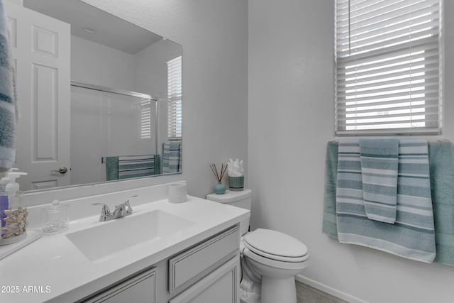 bathroom featuring a shower with door, vanity, and toilet